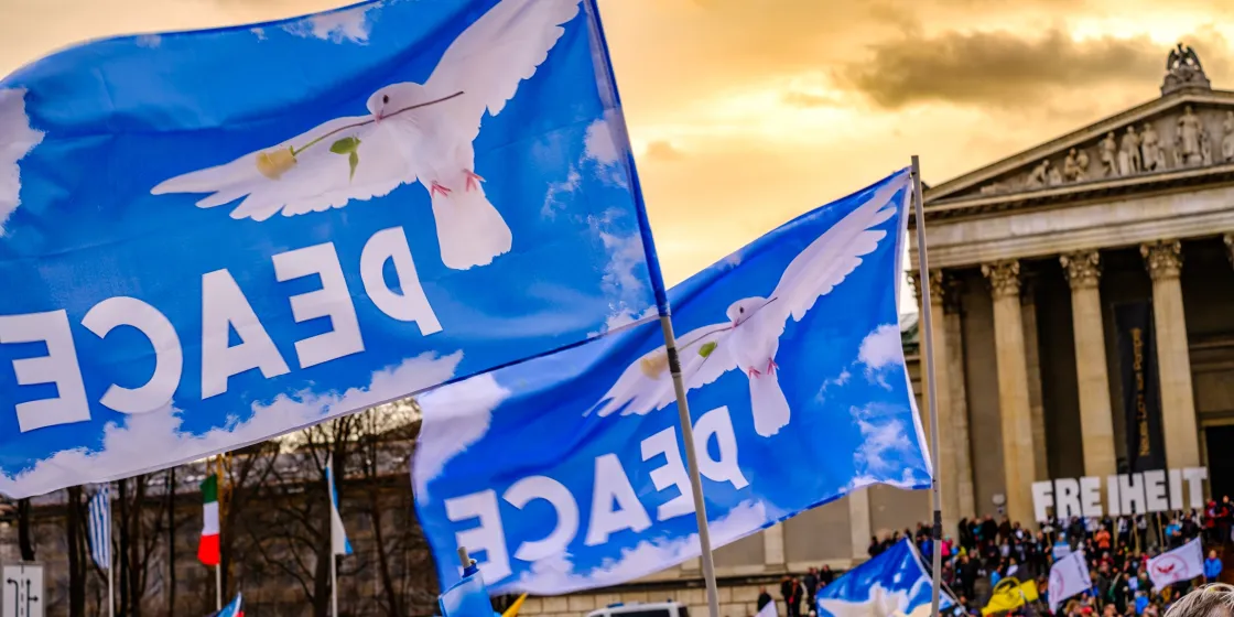 Blaue Flaggen mit Friedenstaube und Schriftzug "Peace" vor Gebäude in München