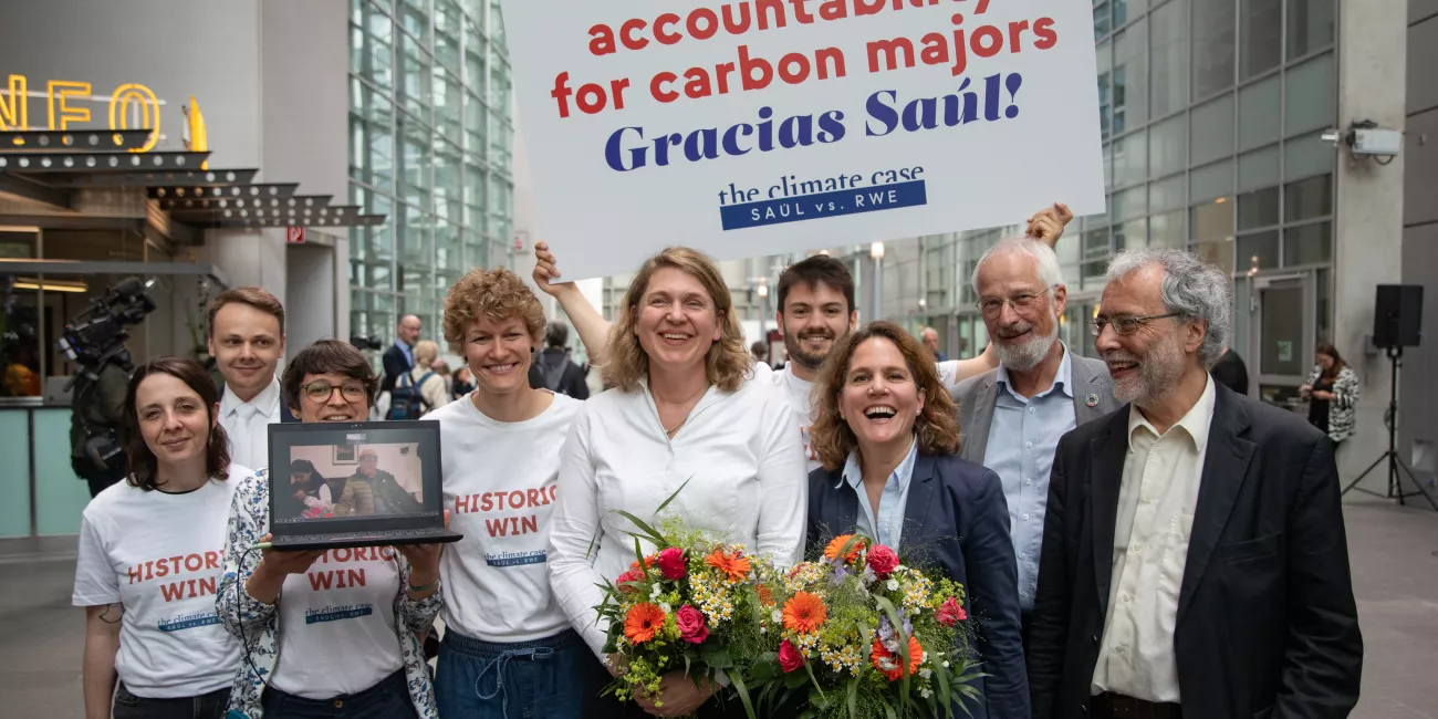 Das Team von Germanwatch & Saúl Anwältin Roda Verheyen im Gerichtssaal. Man erkennt ihnen die Freude im Gesicht an, die beiden Anwältinnen haben einen Blumenstrauß in der Hand