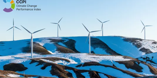 Ein Berg mit Schnee und Windrädern vor blauem Himmel