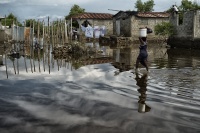 Eine Frau trägt Vorräte über eine überflutete Straße in Cap Haïtien.