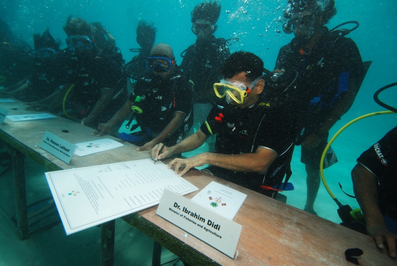 Fig. 3. Maldives Minister of Fisheries and Agriculture Dr. Ibrahim Didi signs decree under water to bring attention to the threat of sea level rise for the Maldives (Mohamed Seeneen / Climate Visuals).