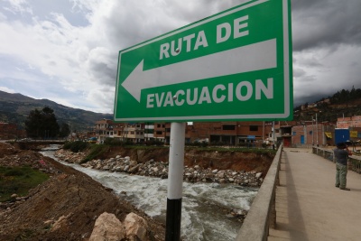 Schild mit der Aufschrift "Ruta de Evacuación" vor einem reißenden Bach