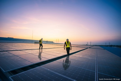 Arbeiter installieren Solarpanels auf einem Dach.