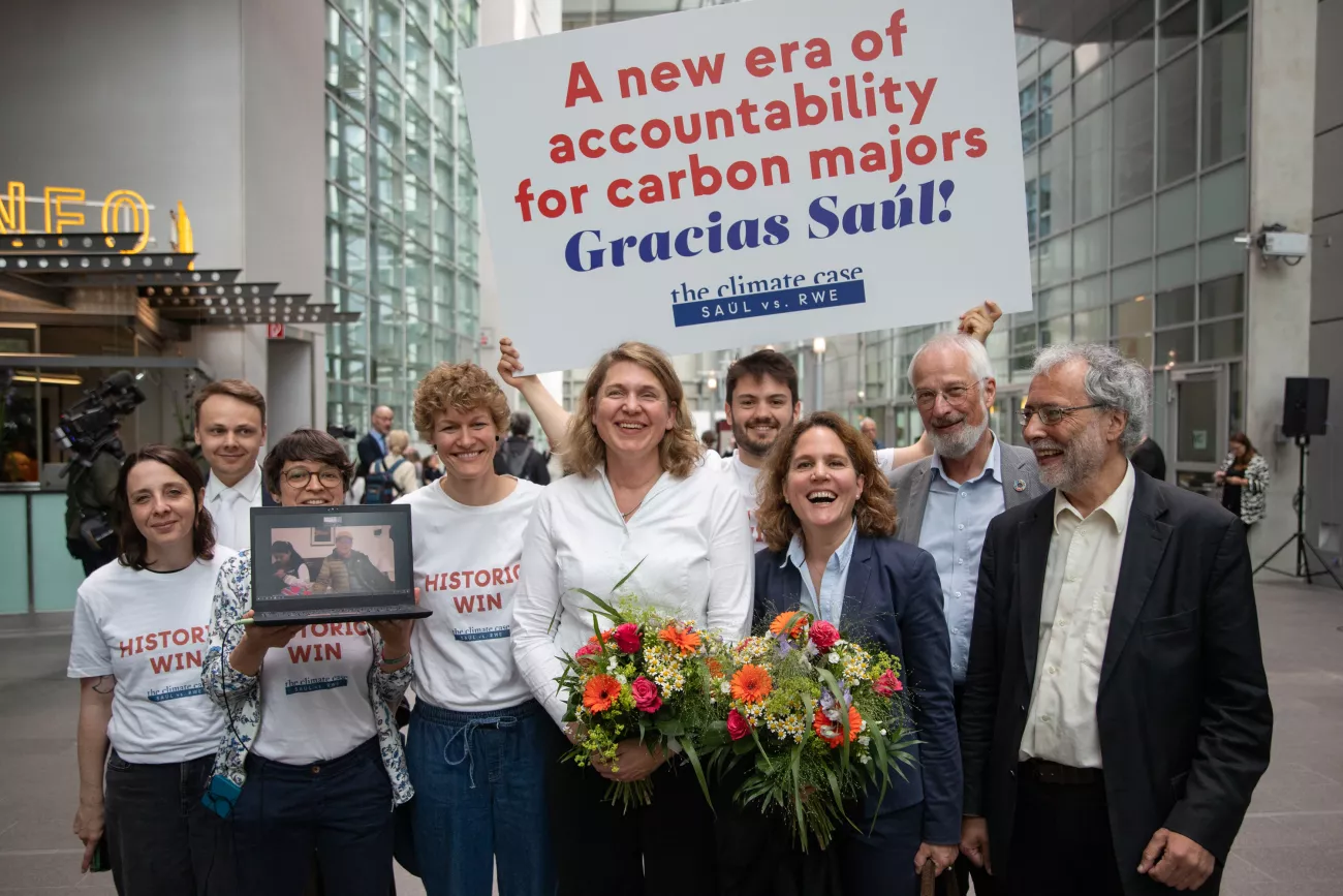 Das Team von Germanwatch & Saúl Anwältin Roda Verheyen im Gerichtssaal. Man erkennt ihnen die Freude im Gesicht an, die beiden Anwältinnen haben einen Blumenstrauß in der Hand