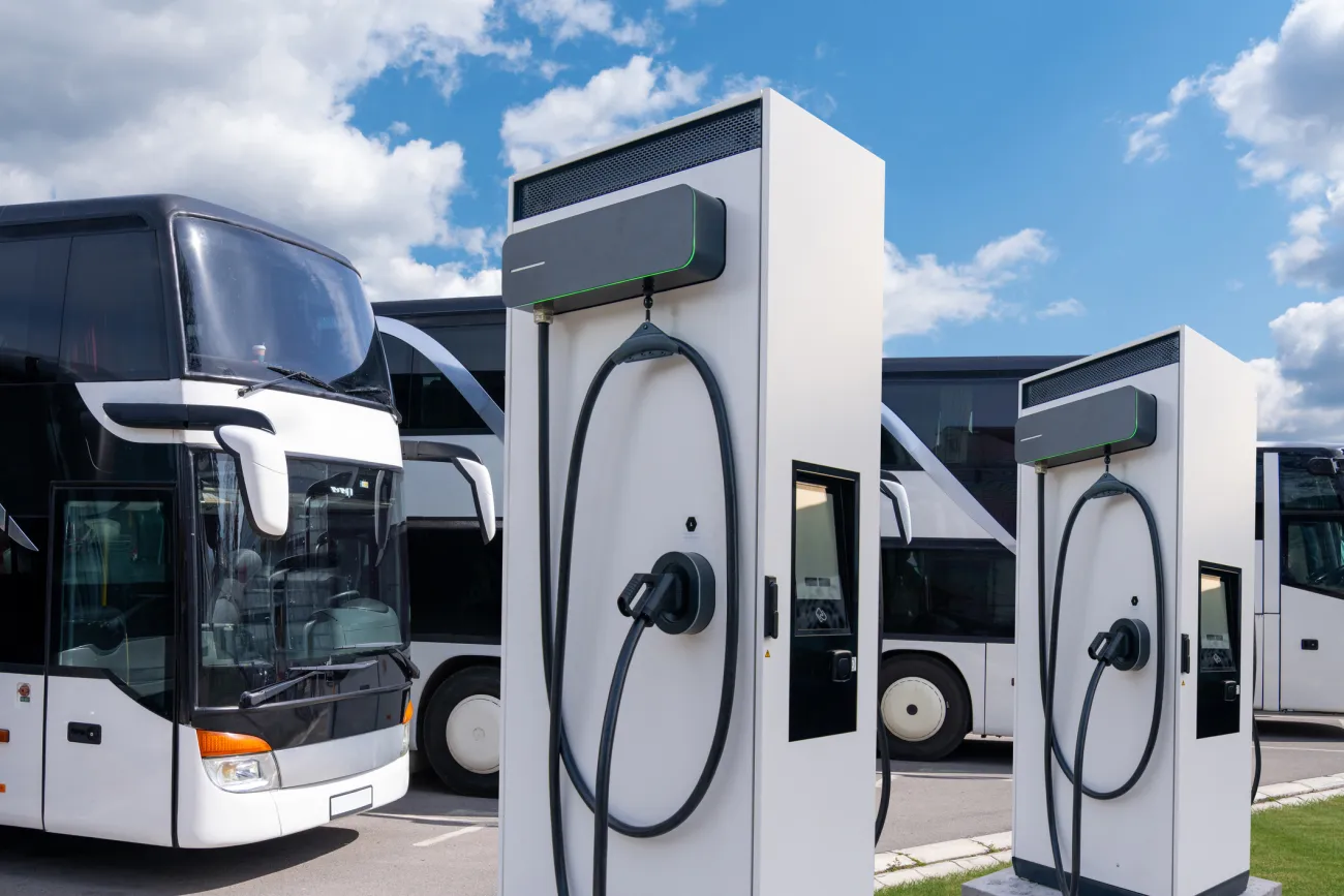 E-Doppeldeckerbusse stehen an Ladesäulen auf Parkplatz