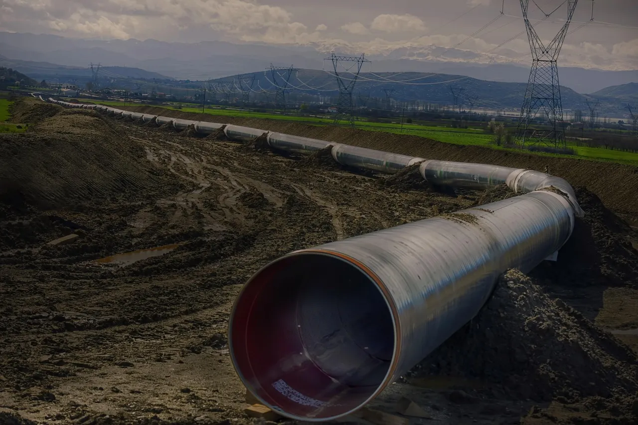 Das Bild zeigt eine ins Leere führende Pipeline. Im HIntergrund sind Hügel und Strommasten zu sehen.