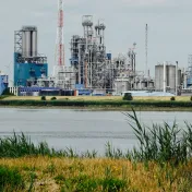 Eine Industrieanlage hitner einem Fuss und grüner Wiese