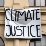 Eine Protestfahne hängt vor einem Gebäude mit der Aufschrift "Climate Justice" (Klimagerechtigkeit)
