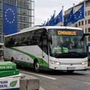 Bus mit Aufschrift Omnibus vor EU-Flaggen