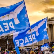 Blaue Flaggen mit Friedenstaube und Schriftzug "Peace" vor Gebäude in München