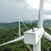 Two workers are standing on a wind turbine in Indonesia