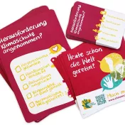 Das Bild enthält eine Postkarte und einen Aufkleber der für die #climatechallenge wirbt.